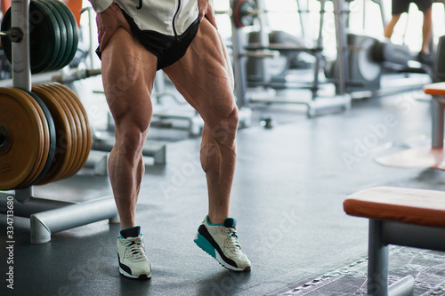 Fototapeta Male muscular athlete bodybuilder show thigh muscles.