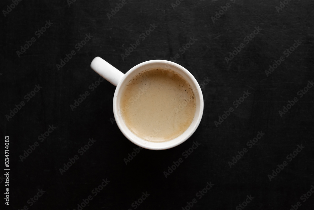 top view of white cup with coffee on a black table top view of white cup with coffee on a black table