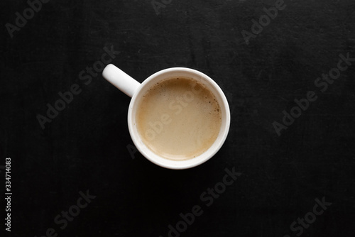 top view of white cup with coffee on a black table