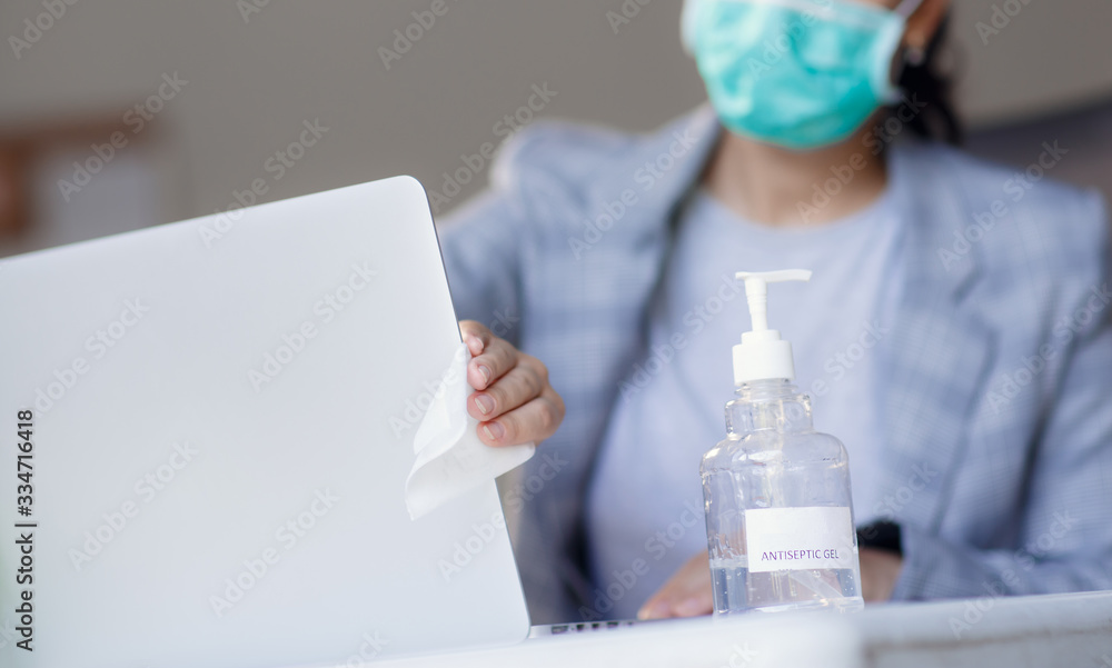 Fototapeta premium Worker disinfects and cleans the laptop and keyboard with antibacterial wet wipes to protect against corona virus covid-19 during pandemic outbreak. Hygiene and virus prevention at work or at home