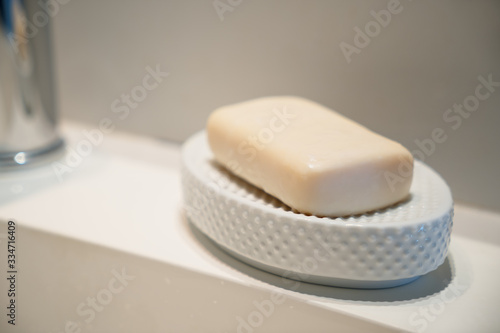 Yellow hand soap in a white ceramic soap dish sitting on a modern white sink selective focus.