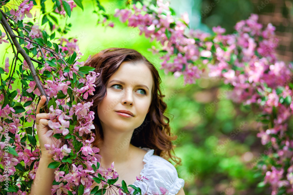 Happy young girl enjoy peach blossom. Spring walk in the blooming garden