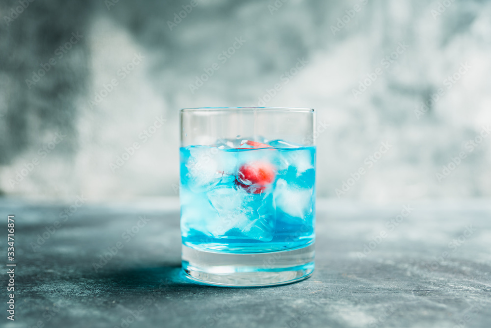 Blue old fashioned cocktail with cherry on the rustic background. Selective focus. Shallow depth of field. Blue old fashioned cocktail with cherry on the rustic background. Selective focus. Shallow depth of field.