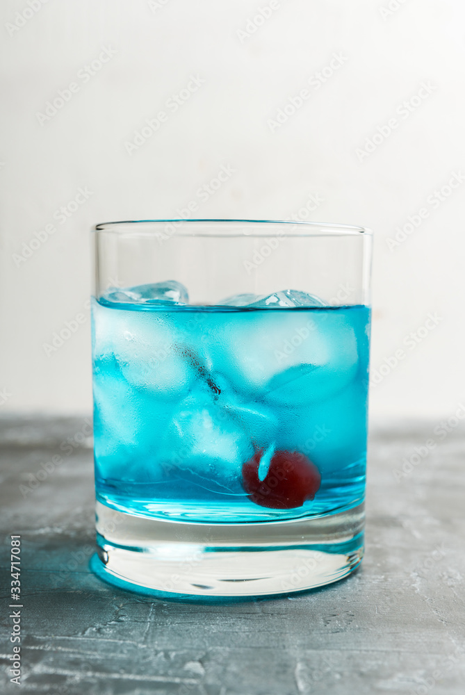 Blue old fashioned cocktail with cherry on the rustic background. Selective focus. Shallow depth of field. Blue old fashioned cocktail with cherry on the rustic background. Selective focus. Shallow depth of field.