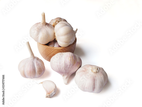 Garlic in wooden bowl and pile garlic cloves isolated on white background.