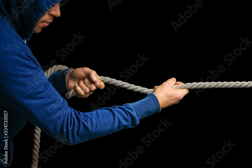 Hands with a rope on a black background. A man pulls a rope wrestling. Drag the business to your side.