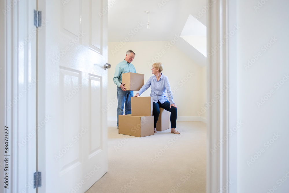 Senior Couple Downsizing In Retirement Carrying Boxes Into New Home On Moving Day Senior Couple Downsizing In Retirement Carrying Boxes Into New Home On Moving Day