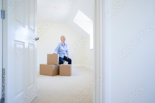 Konstfotografi Senior Woman Downsizing In Retirement Sitting On Boxes In New Home On Moving Day