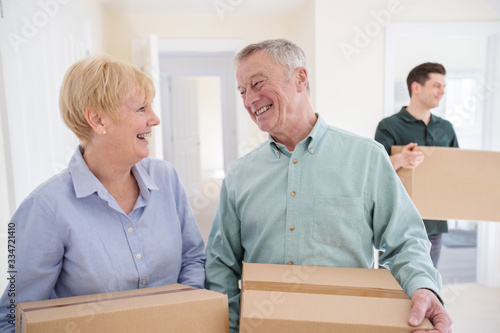 Photos Senior Couple Downsizing In Retirement Carrying Boxes Into New Home On Moving Da