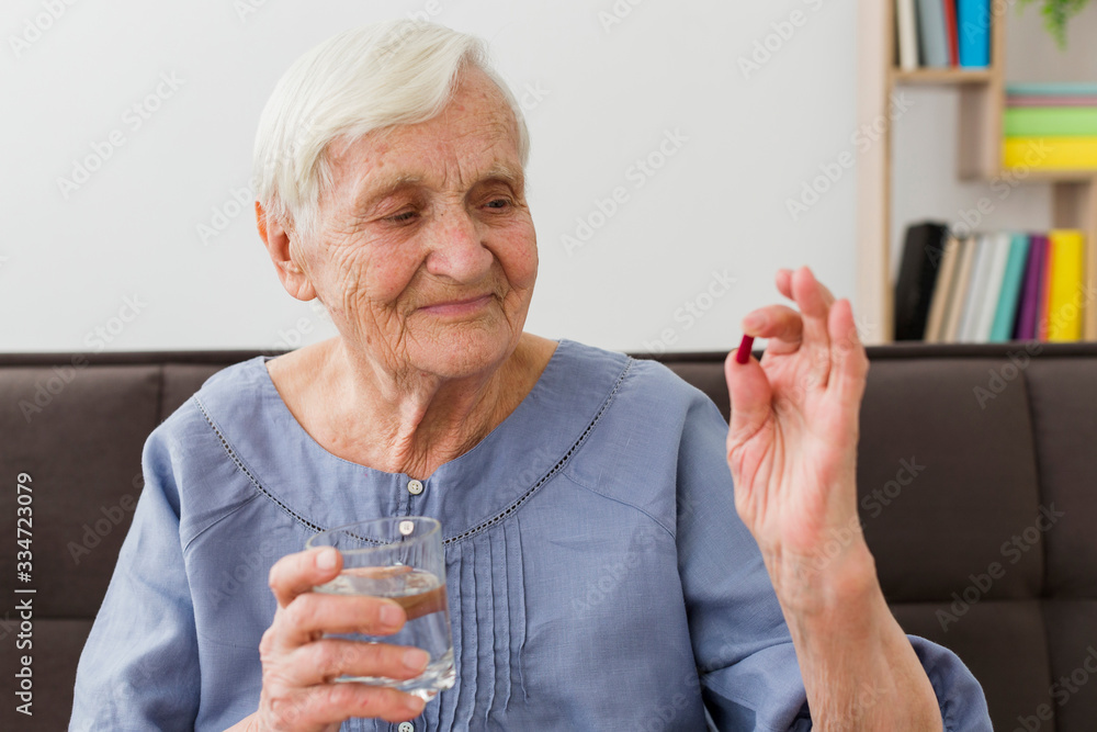 Front view of elderly woman taking her daily pill Front view of elderly woman taking her daily pill
