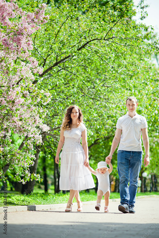 Happy family in the spring garden. Mother father and little daughter together in a blooming Sakura Park. Happy family in the spring garden. Mother father and little daughter together in a blooming Sakura Park.