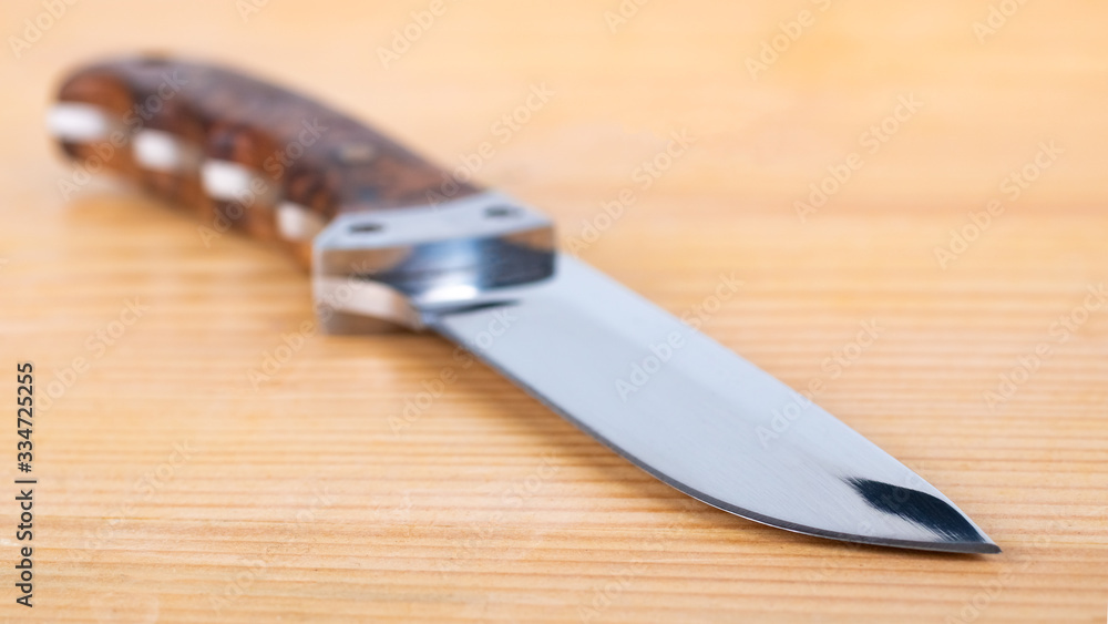 Beautiful hunting knife isolated on the wooden table Beautiful hunting knife isolated on the wooden table