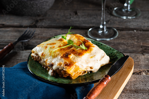 Piece of tasty hot lasagna with red wine. Small depth of field. Traditional italian lasagna. Portion. Italian food. Food on green plate. Bolognese sauce. Bechamel sauce. Still life of food.