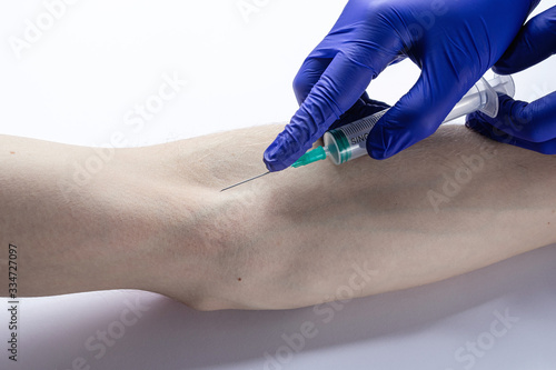 the doctor takes a blood test from a vein with a syringe from a patient