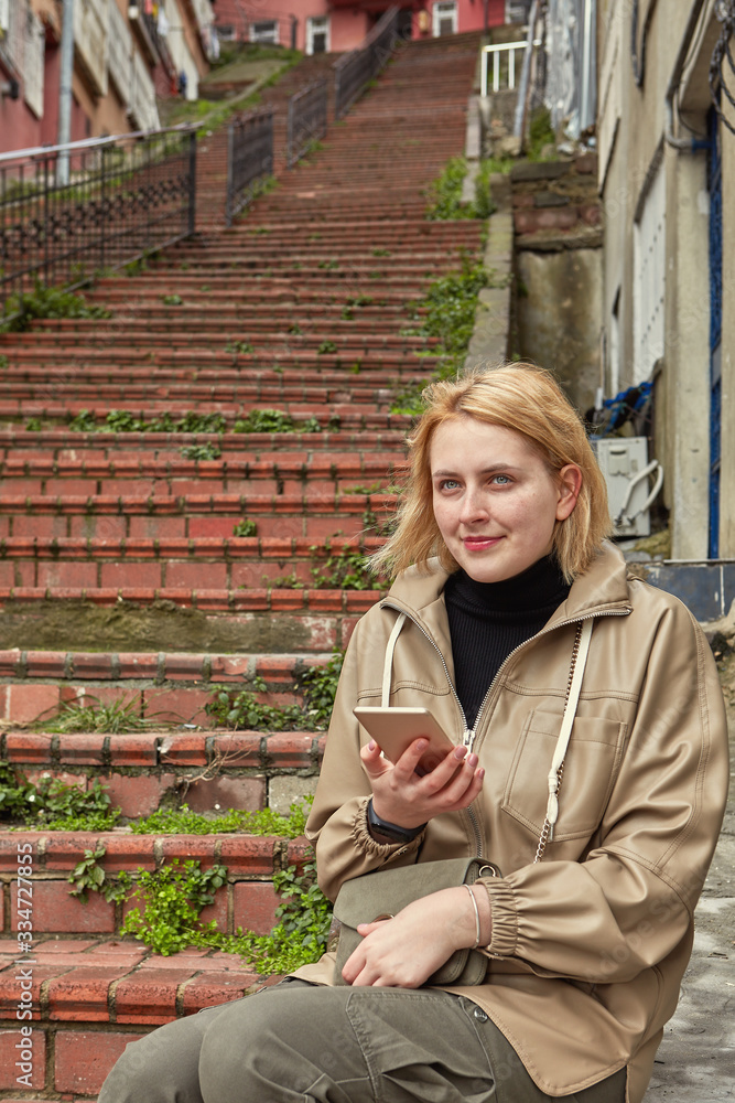 Fototapeta premium Young woman on a walk is studying map on phone.