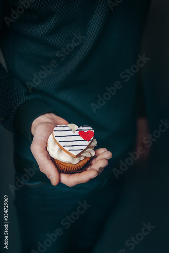 man holds a cupcake with heart
