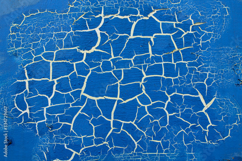 Blue painted surface with white cracks. Cracked blue paint.