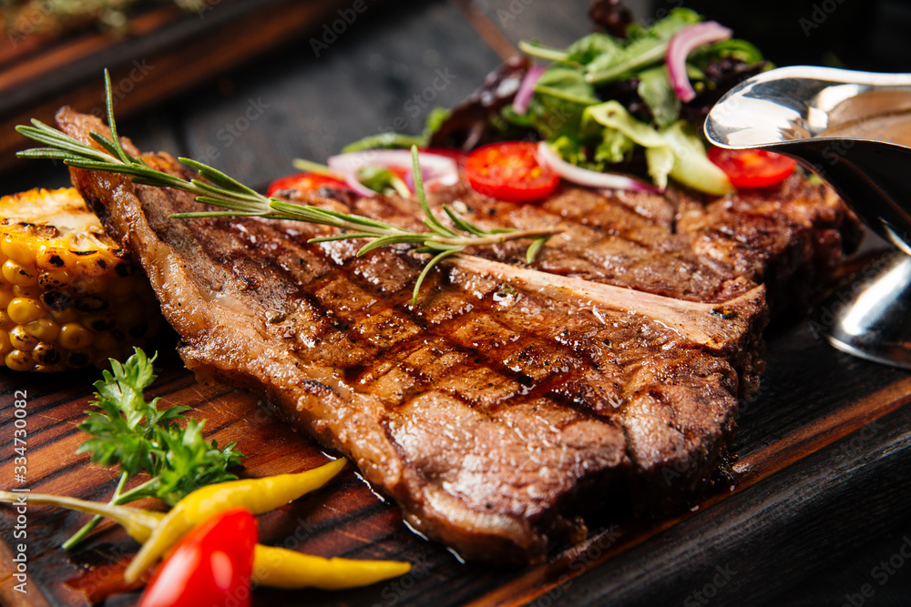 Juicy appetizing steak with tomatoes and rosemary on a wooden board, top view, vertical Juicy appetizing steak with tomatoes and rosemary on a wooden board, top view, vertical