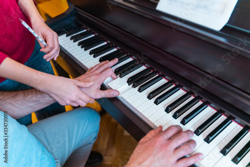 Unrecognizable man learning piano lessons at home. Detail of teacher explaining correct fingering position on classical keyboard. Student practicing index hands on musical instrument. Music concept.