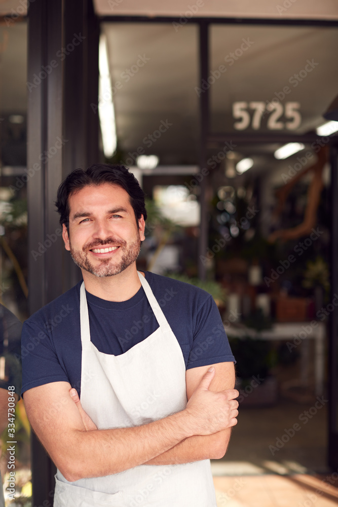 Portrait Of Smiling Male Owner Of Florists Standing In Doorway Surrounded By Plants Portrait Of Smiling Male Owner Of Florists Standing In Doorway Surrounded By Plants