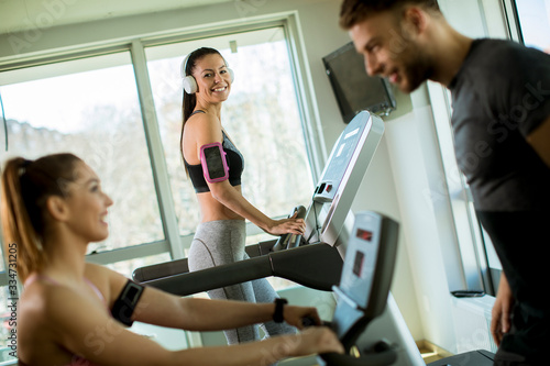 Young woman using treadmill in modern gym