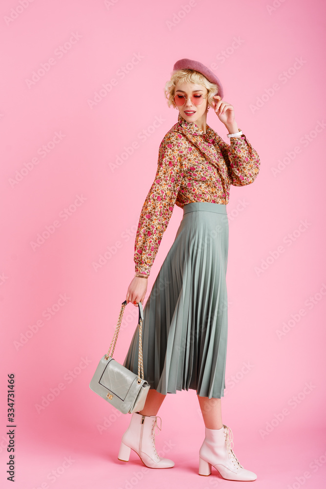 Full-length studio fashion portrait of young elegant happy smiling woman wearing trendy spring outfit: floral print blouse, green pleated skirt, white ankle boots, holding stylish  faux leather bag - obrazy, fototapety, plakaty 