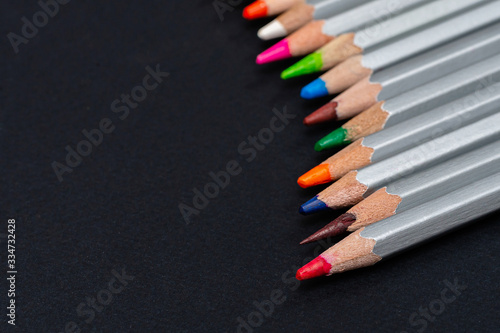 gray wooden pencils with colored rods on a black background