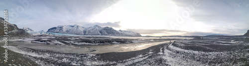 A mountain full of snow right in front of a black sand beach