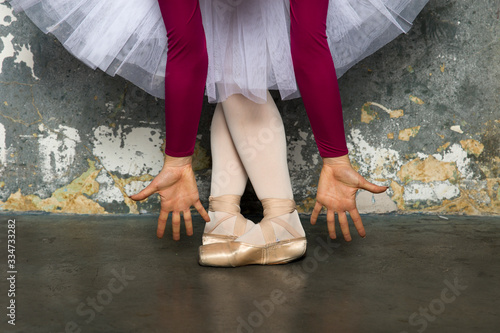 Young ballerina dancer dancing classical ballet against rustic wall