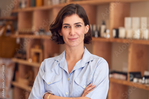Фотография Portrait Of Female Owner Of Gift Store Standing In Front Of Shelves With Cosmeti