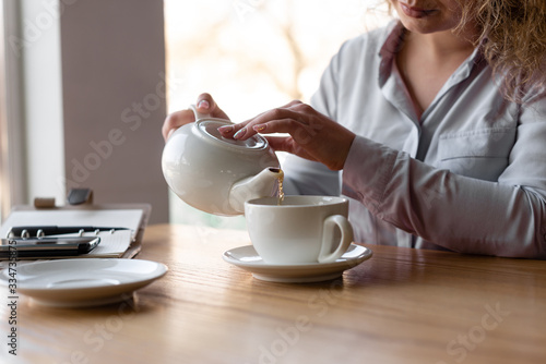 Fotografija Closeup of the hand of a girl who pours herself tea.