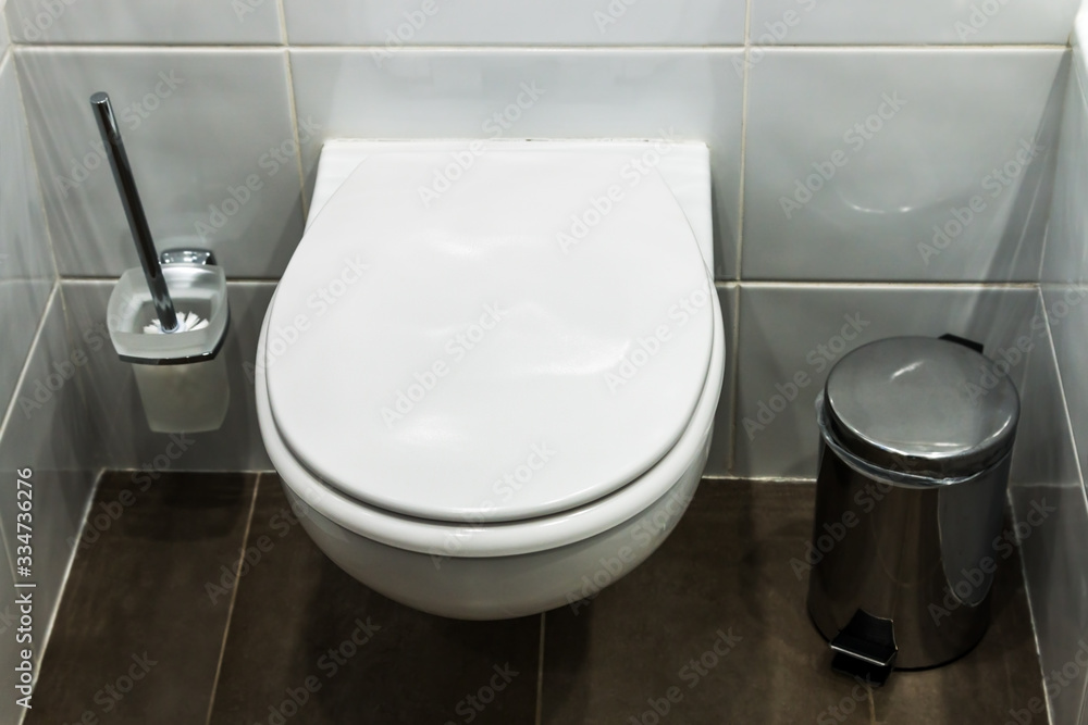 Fototapeta premium toilet bowl and cleaning brush for cleaning the toilet bowl in the toilet room. Focus in the middle of the frame on the toilet cover