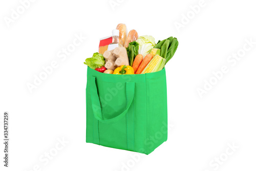 Green reusable shopping bag full of vegetables and groceries isolated on white background