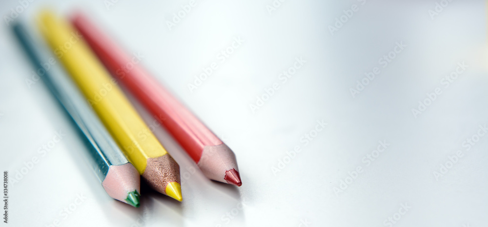 Fototapeta premium Three color pencils - red, yellow, green on a white background. Concept - school, education, art education