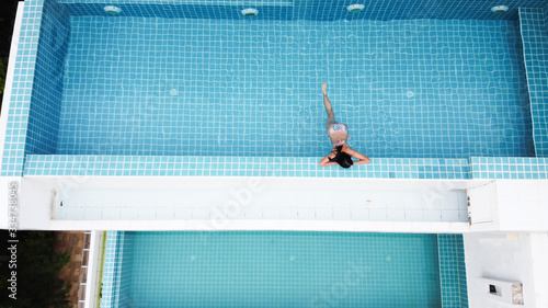 Aerial view of young woman relaxing in swimming pool.