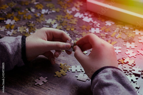 Hands of a teenager put a puzzle on the table. Concept quarantine and self-isolation.
