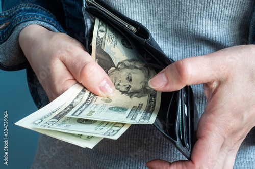 Women's hands take money dollars out of their wallets.