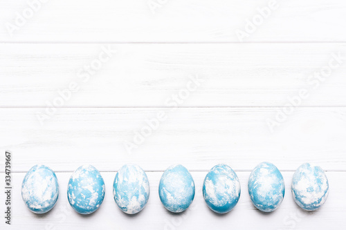 Happy Easter background. Painted Easter eggs on white wooden background, top view