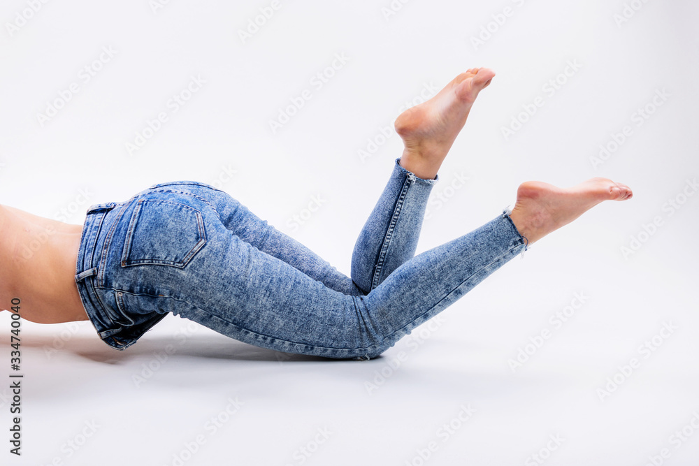 Close up of a beautiful woman legs in blue jeans and barefoot isolated on a  gray background Stock Photo | Adobe Stock