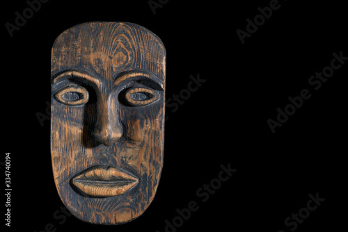 African mask carved from wood on a black background. Free space, black background