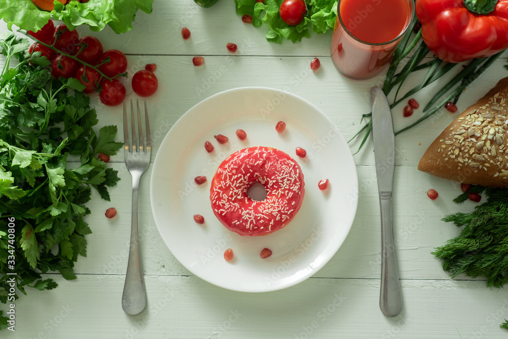 A delicious donut lies on a plate and eats to eat it. Problems of proper nutrition and the concept of choosing between wholesome and not wholesome food A delicious donut lies on a plate and eats to eat it. Problems of proper nutrition and the concept of choosing between wholesome and not wholesome food