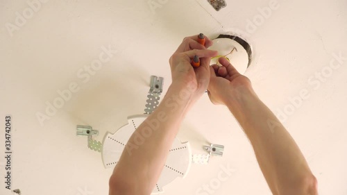 An electrician pulls wires through a ceiling fan box. Coding work is performed by a licensed master electrician. removes unnecessary for the installation of a stretch ceiling. chandelier, floor lamp, photo