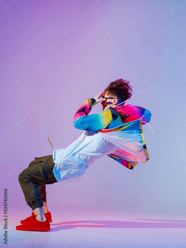Guy dancing contemporary dance in studio. Neon light grey background