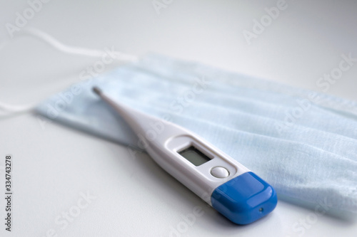Thermometer on a medical mask in blue on a white background. Coronavirus Precautions Mask Protection.