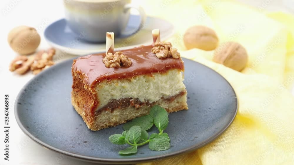 Male hand decorate a homemade caramel cheesecake with mint on a white wooden background and yellow textile. Side view, close up. Male hand decorate a homemade caramel cheesecake with mint on a white wooden background and yellow textile. Side view, close up.