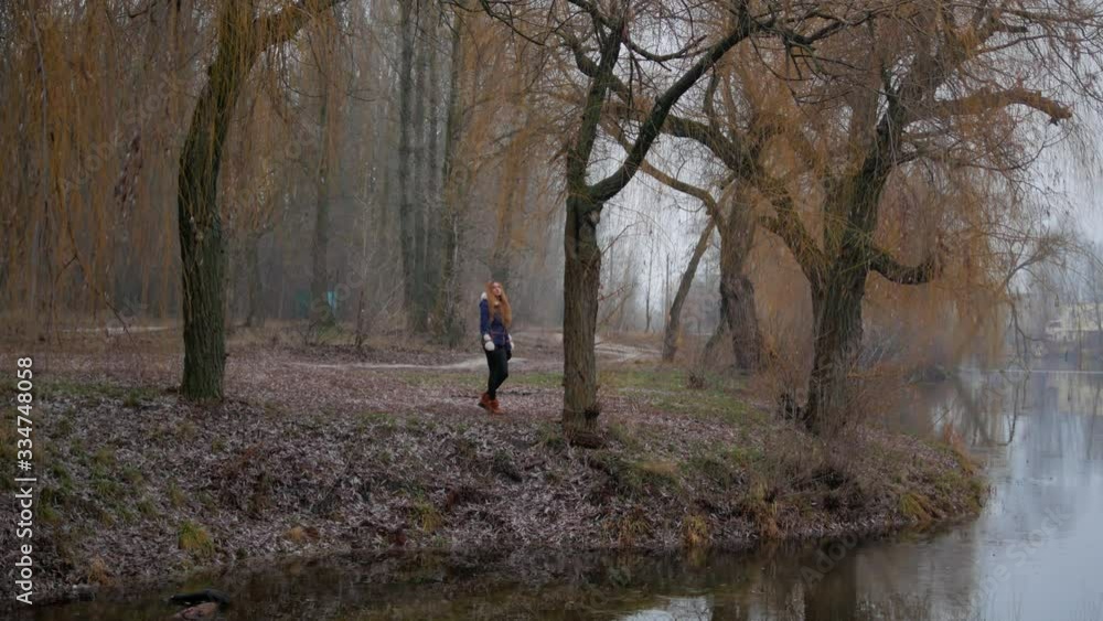 young woman lonely walking in autumn park with river young woman lonely walking in autumn park with river