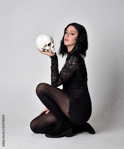 Принти на полотні Portrait of a goth girl with dark hair wearing black lace dress and boots