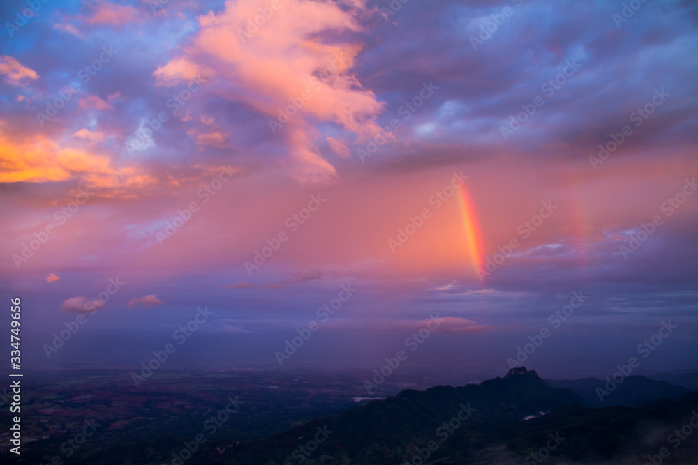 rainbow in colorful clouds over mountain