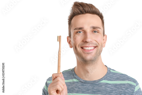 Handsome young man with toothbrush on white background