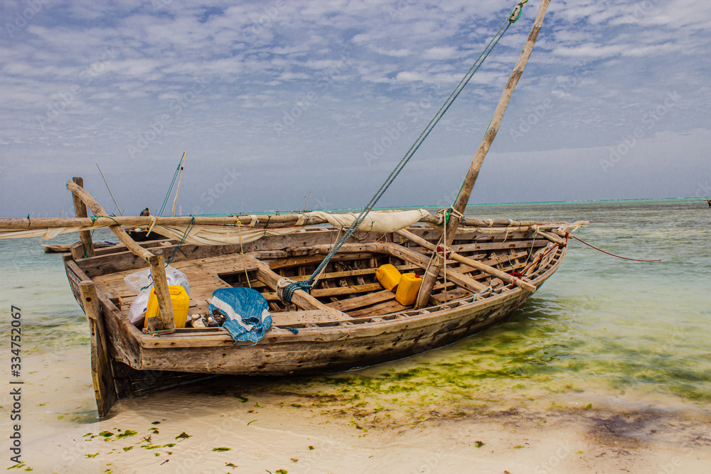 Fishermen traditional boat dhow on the shore of the ocean in Nungwi, Tanzania. Colourful photo showing simple living in Africa, Tanzania, Zanzibar. Idyllic place to travel and see beautiful places Fishermen traditional boat dhow on the shore of the ocean in Nungwi, Tanzania. Colourful photo showing simple living in Africa, Tanzania, Zanzibar. Idyllic place to travel and see beautiful places
